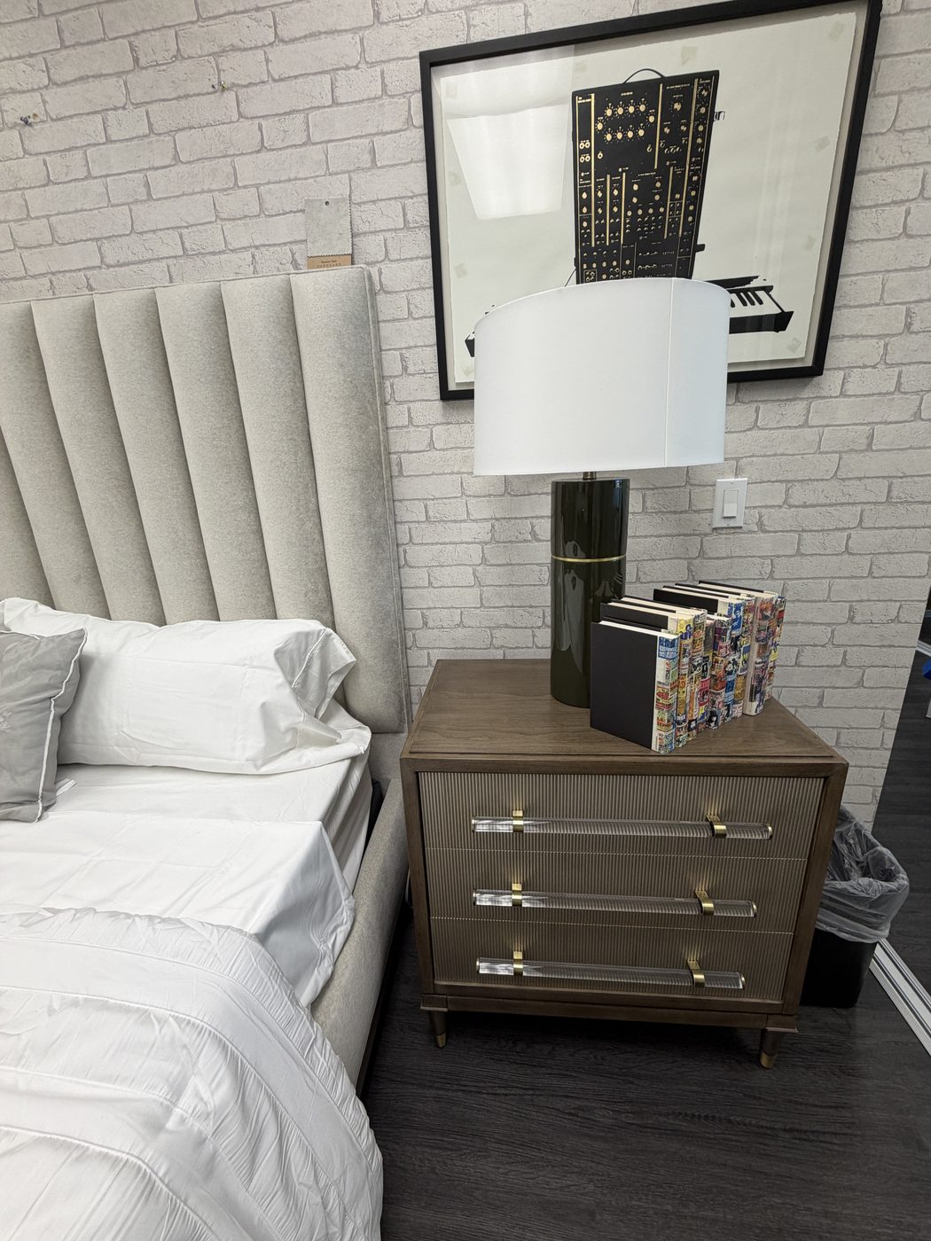 Detail of a reeded Vanguard nightstand with acrylic and brass drawer pulls, paired with a channel-tufted headboard and an emerald green ceramic lamp